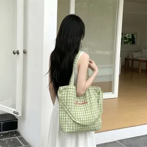Detail of light green plaid canvas tote bag with red Sozakka embroidery on soft fabric