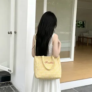 Detail of yellow checkered canvas tote bag with red Sozakka embroidery and dual straps