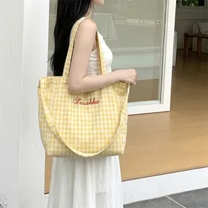 Detail view of yellow gingham canvas tote bag featuring Sozakka floral embroidery