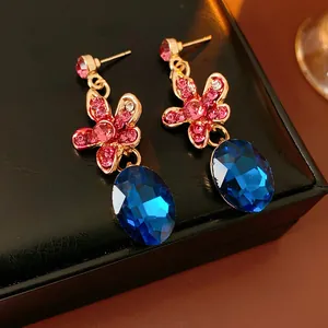 Detailed view of floral earrings featuring pink diamonds and oval blue gemstones