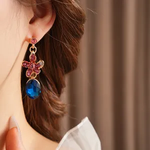 Detail of floral tassel earring with blue oval gemstone and pink crystal accents