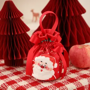 Close-up of a red velvet Christmas drawstring gift bag with a cute Santa Claus pattern