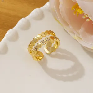Close-up of golden honeycomb open ring with micro-paved crystals on white ceramic tray