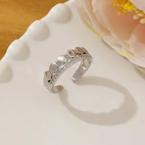 Close-up of a silver hexagonal micro-pave ring on a white plate with floral accents