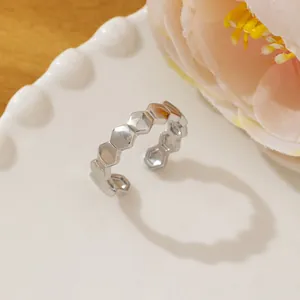 Detail shot of a silver honeycomb geometric ring on a ceramic plate with flowers