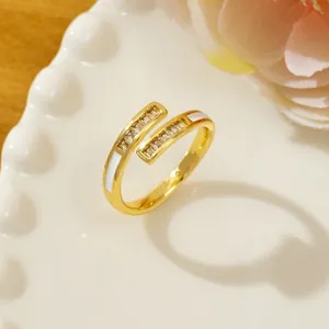 Detail of gold open ring with rectangle zircons and white enamel on a white ceramic plate
