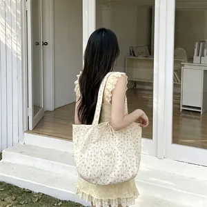 Detailed side view of floral chiffon tote bag featuring tie closure and woven brand label