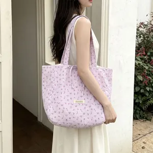 Detailed close-up of quilted floral shoulder bag in light purple with soft cotton texture