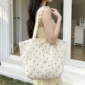 Close-up of beige quilted tote bag featuring floral patterns and soft fabric texture