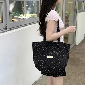 Detailed view of black floral quilted tote bag with yellow print and logo patch on model