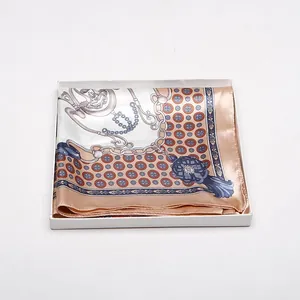 Detail eines Seidenschals mit Vintage-Kettenmuster, gefaltet in einer weißen Geschenkbox