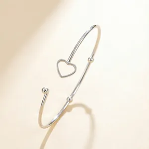Minimalist silver stainless steel open heart bracelet with polished beads on textured background