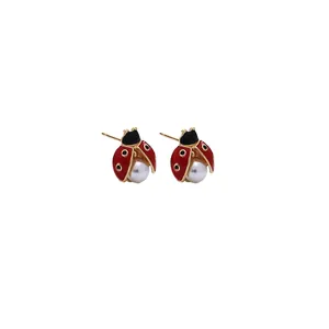 Détail de boucles d'oreilles coccinelle en émail rouge et noir avec perle blanche