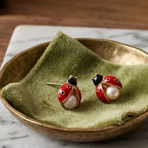 Gros plan détaillé des boucles d'oreilles coccinelle avec émail rouge et perle