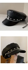 Close-up of black PU leather newsboy cap with silver anchor badge and chain detail