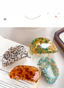 Detail shot of acetate claw clips in leopard and marble patterns on a book background