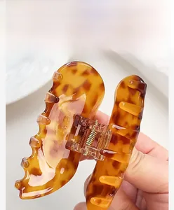 Detailed close-up of tortoiseshell acetate hair claw clip with golden metal spring
