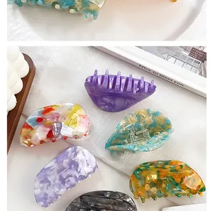 Various acetate hair claws in marble and amber colors displayed on a soft white cloth