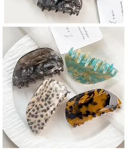Detail view of four acetate hair claws in tortoiseshell, leopard, and marble patterns
