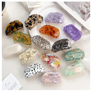 Macro shot of assorted tortoise shell and marble acetate claw clips on a white tray