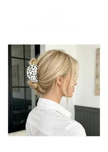 Close-up of a white acetate hair claw clip with black stars worn on blonde hair