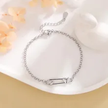 Detail of bunny bracelet with safety pin and heart charm in a white ceramic dish