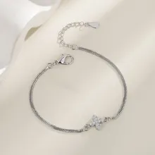 Detail of silver snake chain bracelet with a sparkling rhinestone-encrusted cross pendant