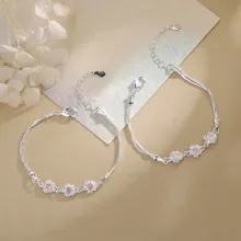 Close-up of flower bracelets with pink and white zircons and silver-plated chains