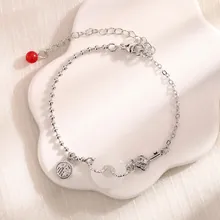 Detail of silver bead chain bracelet featuring faux jade ring and Fu character tag