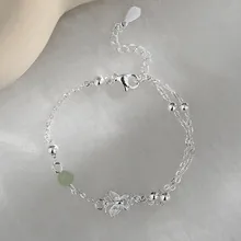 Detailed macro view of silver chain bracelet featuring hollow butterfly and green bead