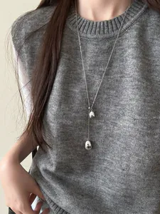 Detail of silver waterdrop pendant on a long Y-shaped chain for minimal sweater styling