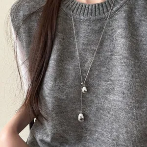 Elegant silver Y-shaped necklace with double waterdrop pendants on a grey sweater