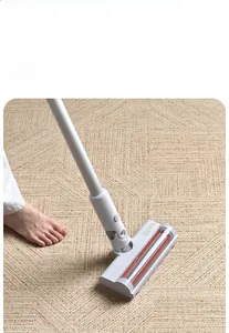 Detail view of electric floor brush head with red spiral roller on beige textured carpet