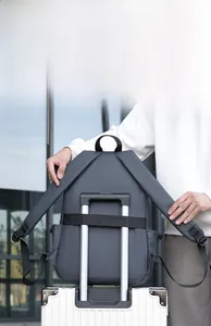 Detail of dark grey backpack with a trolley sleeve attached to a white suitcase handle