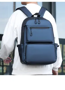 Rear view of a navy blue waterproof laptop backpack with multi-pocket design on model