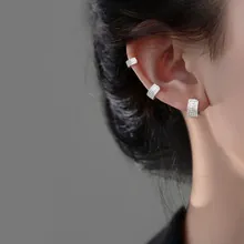 Close-up of geometric silver ear cuff set with pavé stones worn on a model's ear