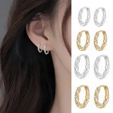 Close-up of twisted rope huggie earrings with zircon inlays in gold and silver