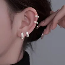 Macro detail of silver wave earrings with pavé zircons on model ear