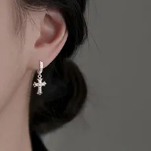 Macro shot of silver gothic cross earring with embossed textures and vintage finish