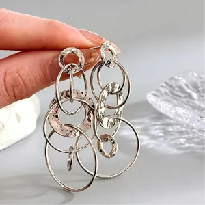 Gros plan de boucles d'oreilles argentées multi-anneaux avec finitions martelées et miroirs