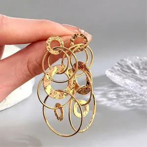 Détail de boucles d'oreilles créoles dorées avec texture martelée et finition métallique