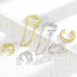 Detalle de un conjunto de pendientes ear cuff dorados y plateados con cadenas y cristales