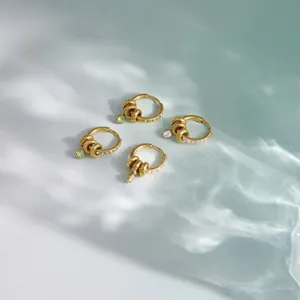 Vue détaillée de boucles d'oreilles en acier doré avec zircons verts et blancs brillants