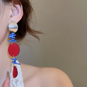 Détail d'une boucle d'oreille asymétrique géométrique avec des formes en résine rouge