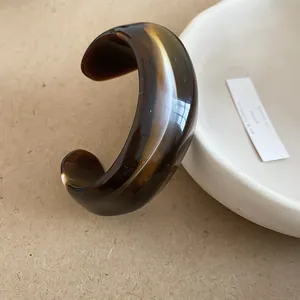 Irregular tortoise shell resin open bangle bracelet with a glossy marble texture finish