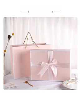 Pink gift box set with ribbon bow and gold handles on marble surface for weddings