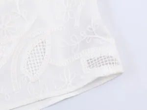 Detailed close-up of white floral embroidery and hollow mesh on the hem of a stylish shirt