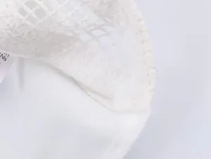 Close-up of white mesh fabric texture and wash care label on an embroidered shirt
