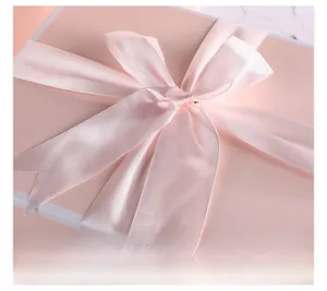 Close-up of elegant pink satin ribbon bow on minimalist gift box lid packaging