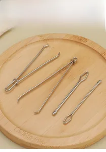 Macro view of 4-piece stainless steel bodkin threader set on a wooden tray